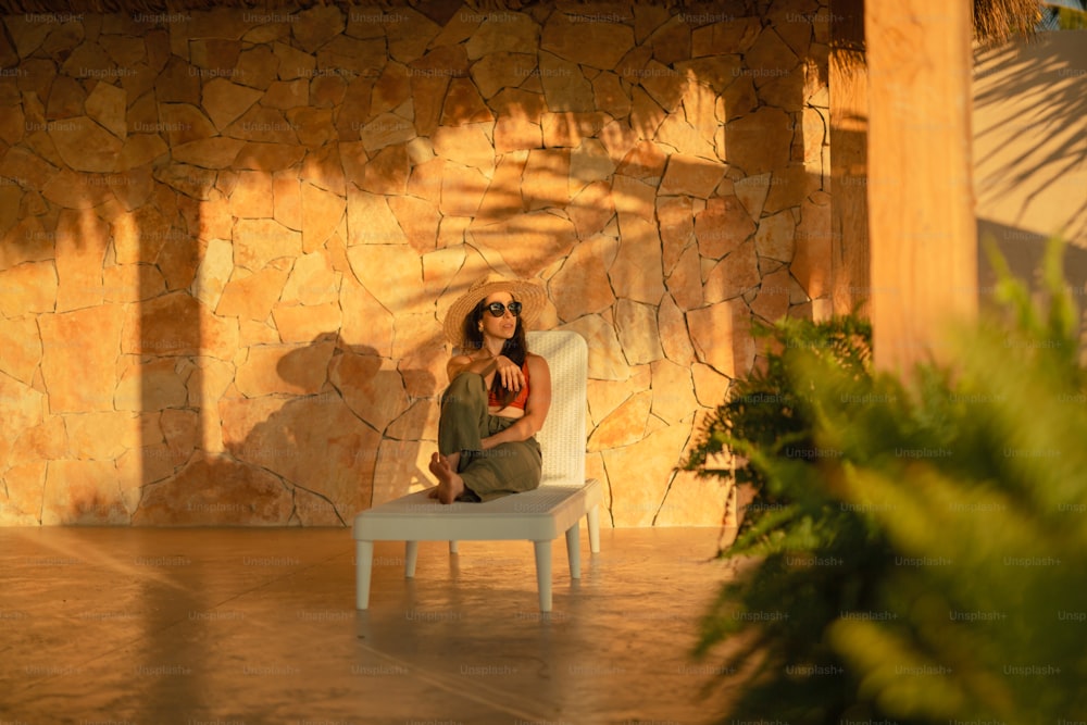 a woman sitting on a chair in front of a stone wall