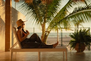 Une femme en chapeau de paille assise sur une chaise de plage