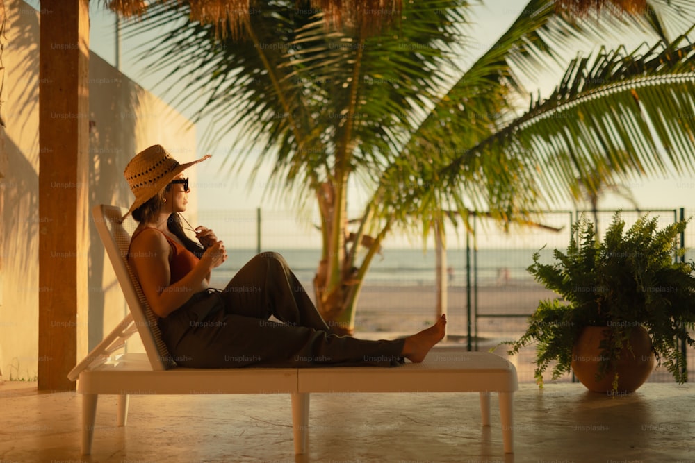 uma mulher em um chapéu de palha sentado em uma cadeira de praia