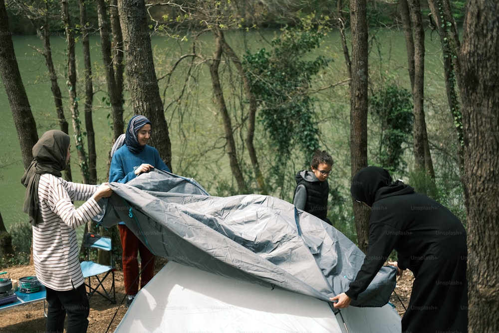 a group of people setting up a tent in the woods