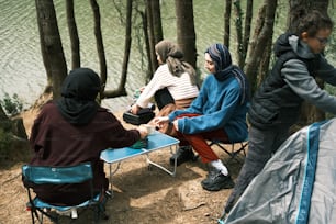 Un gruppo di persone sedute attorno a un tavolo vicino a un lago