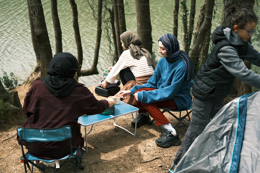 a group of people sitting around a table next to a lake