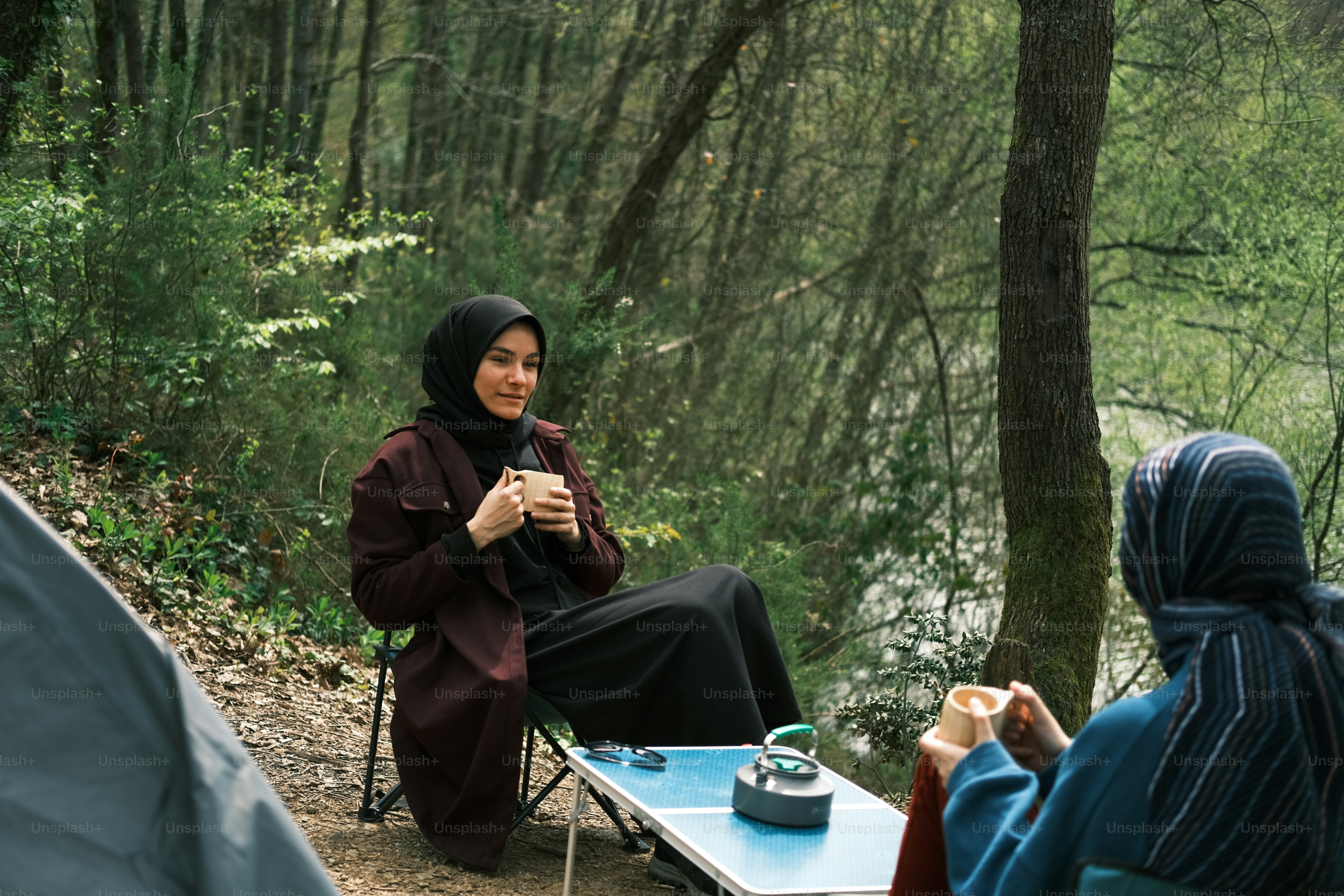 a woman in a hijab sitting at a table with a cup of coffee