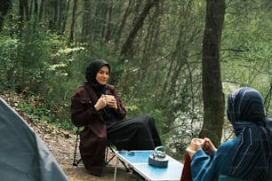 a woman in a hijab sitting at a table with a cup of coffee