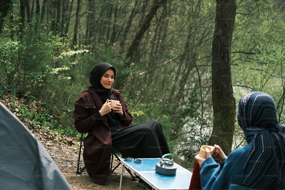 Una mujer con un hijab sentada en una mesa con una taza de café