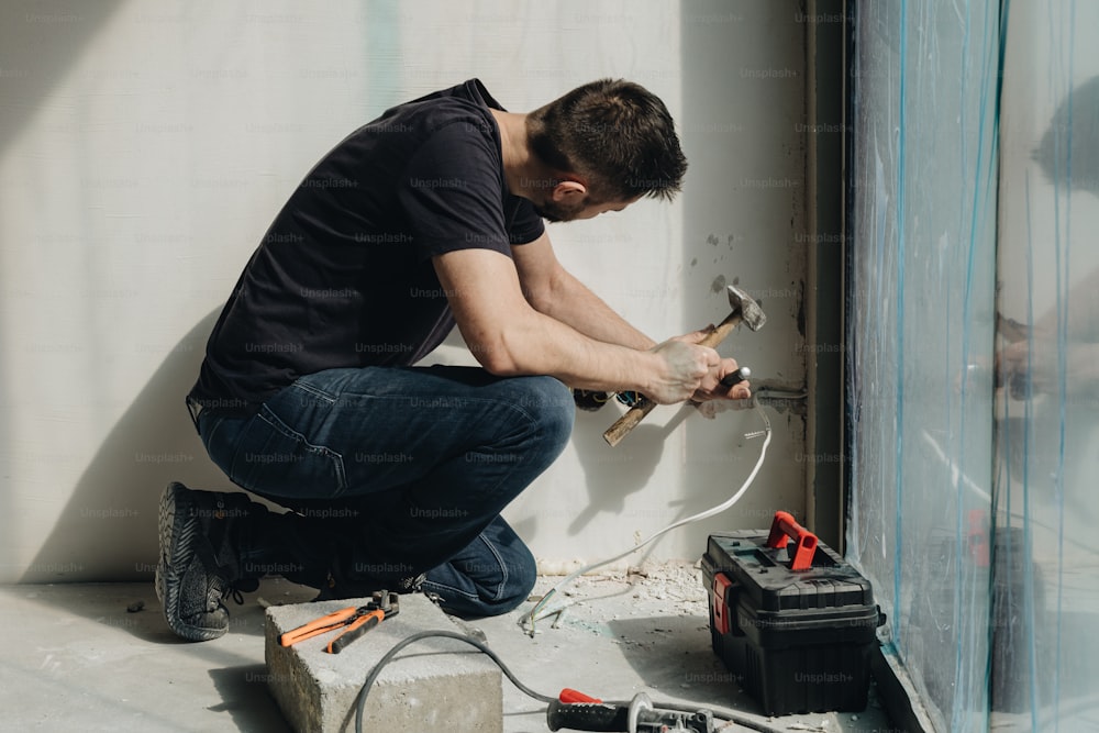 Un hombre trabajando en una pared con herramientas