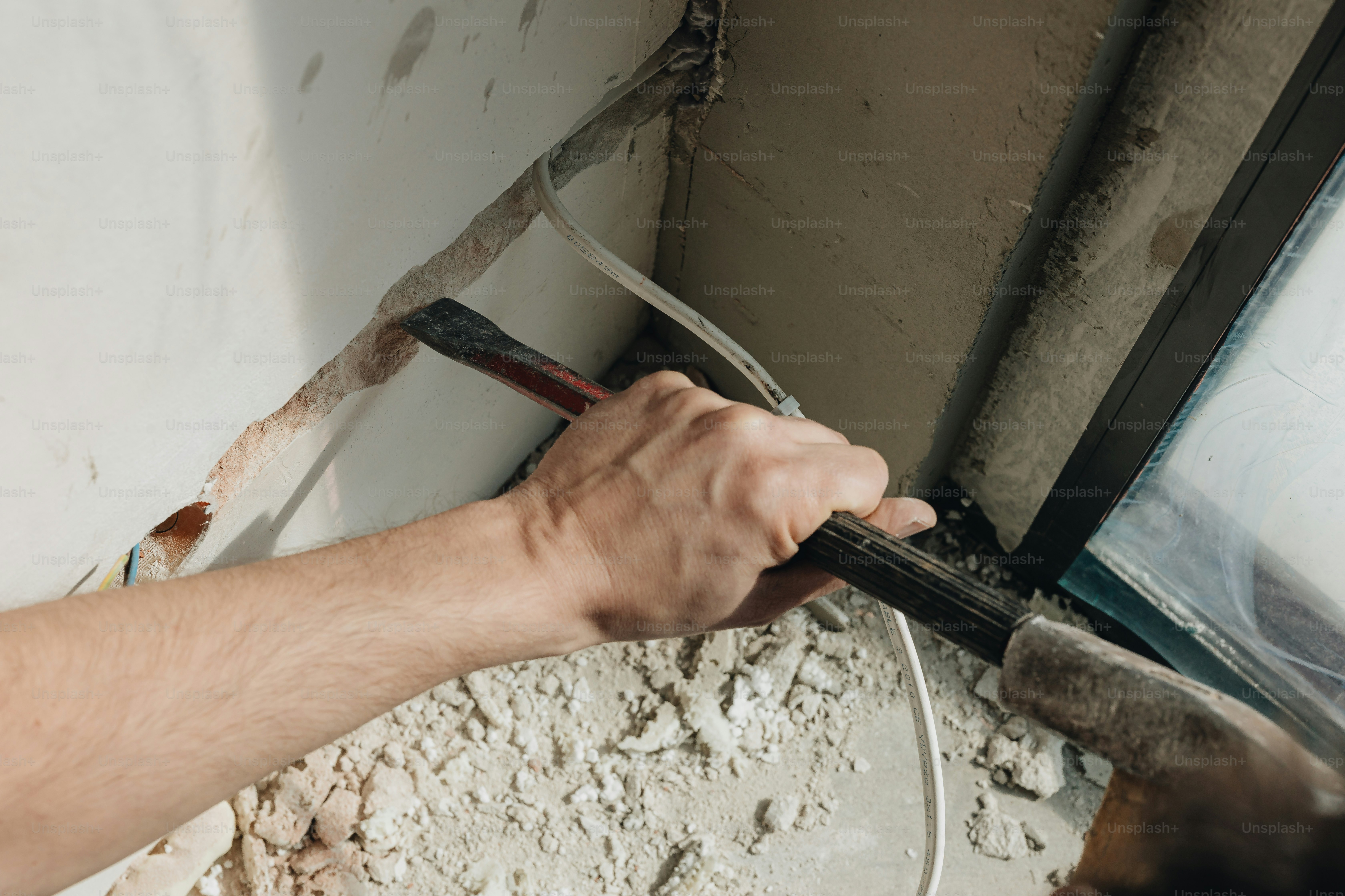 a man is working on a wall with a hammer