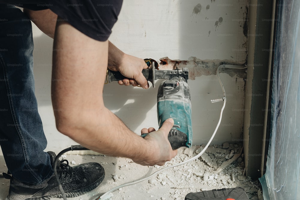 Ein Mann, der eine Bohrmaschine benutzt, um ein Loch in einer Wand zu reparieren