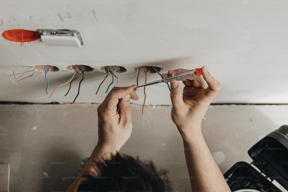 a man working on a ceiling with electrical wires