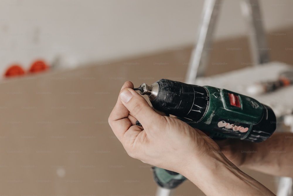 a person holding a cordless drill in their hand