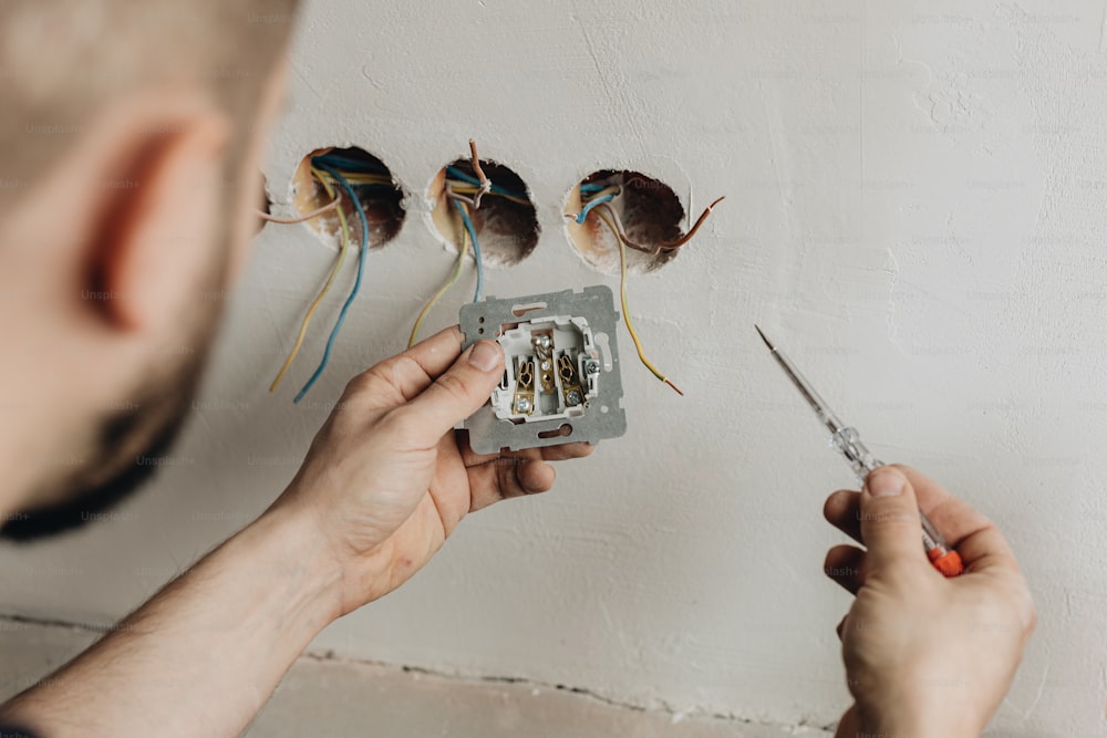 a man holding a pair of scissors in front of a light switch