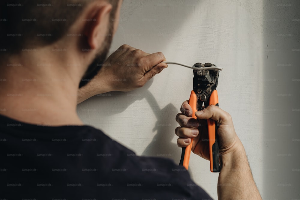 Un hombre está trabajando en una pared con un par de alicates