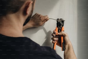 a man is working on a wall with a pair of pliers