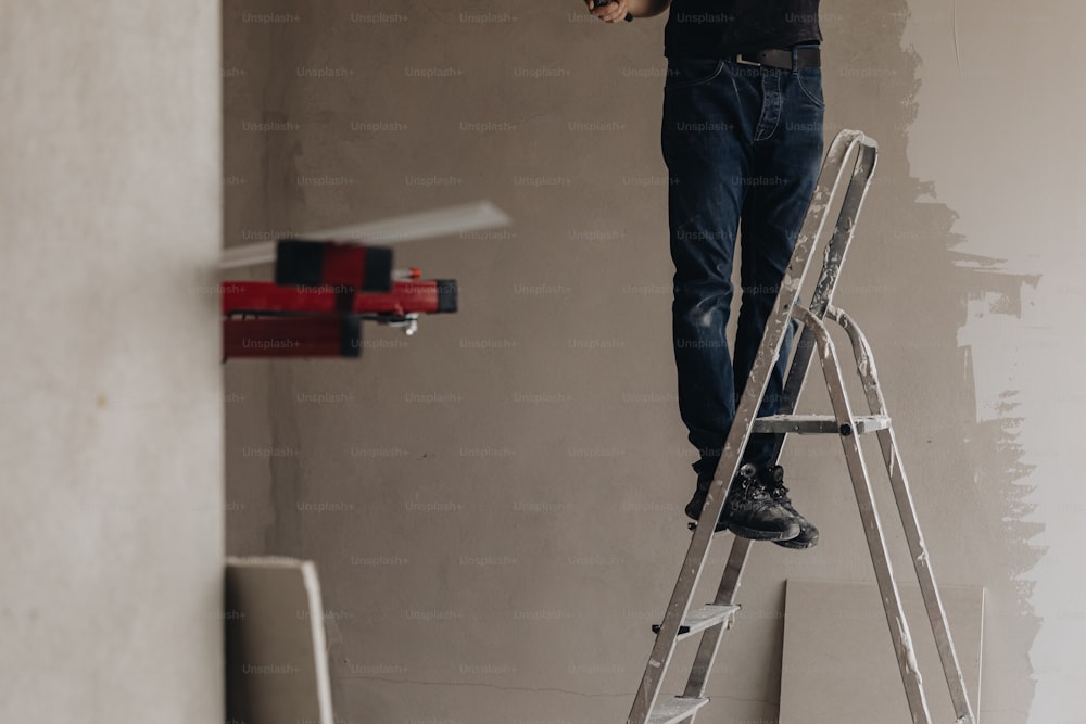 Ein Mann, der auf einer Trittleiter steht und eine Wand bemalt