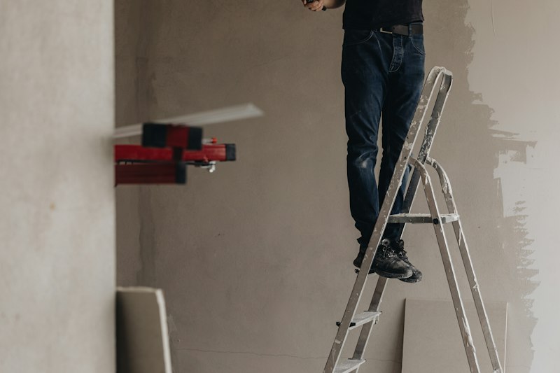 Storefront technician using laser level for precise commercial building repair