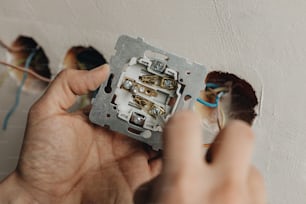 a person is fixing a light switch on a wall