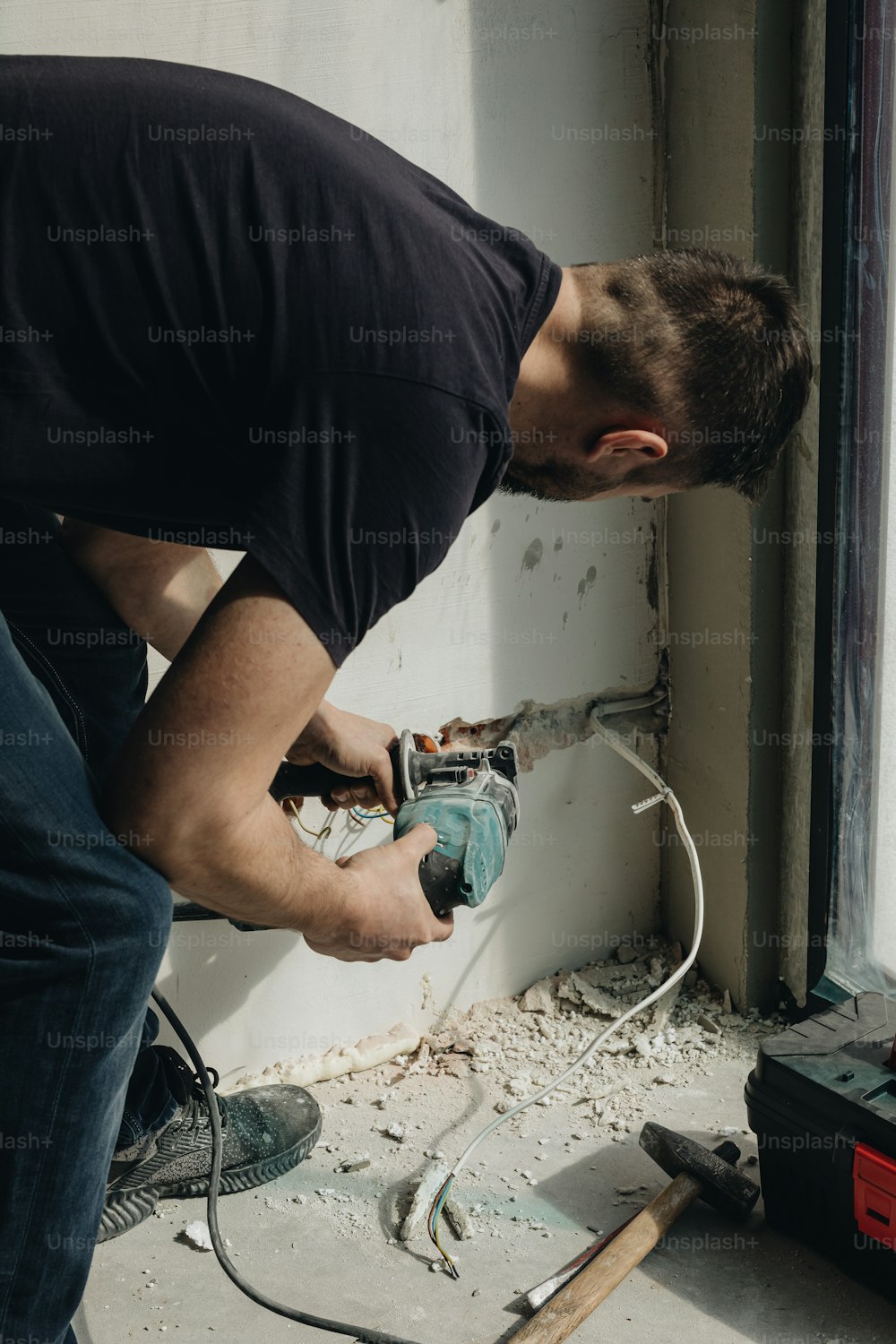 a man working on a wall with a power drill
