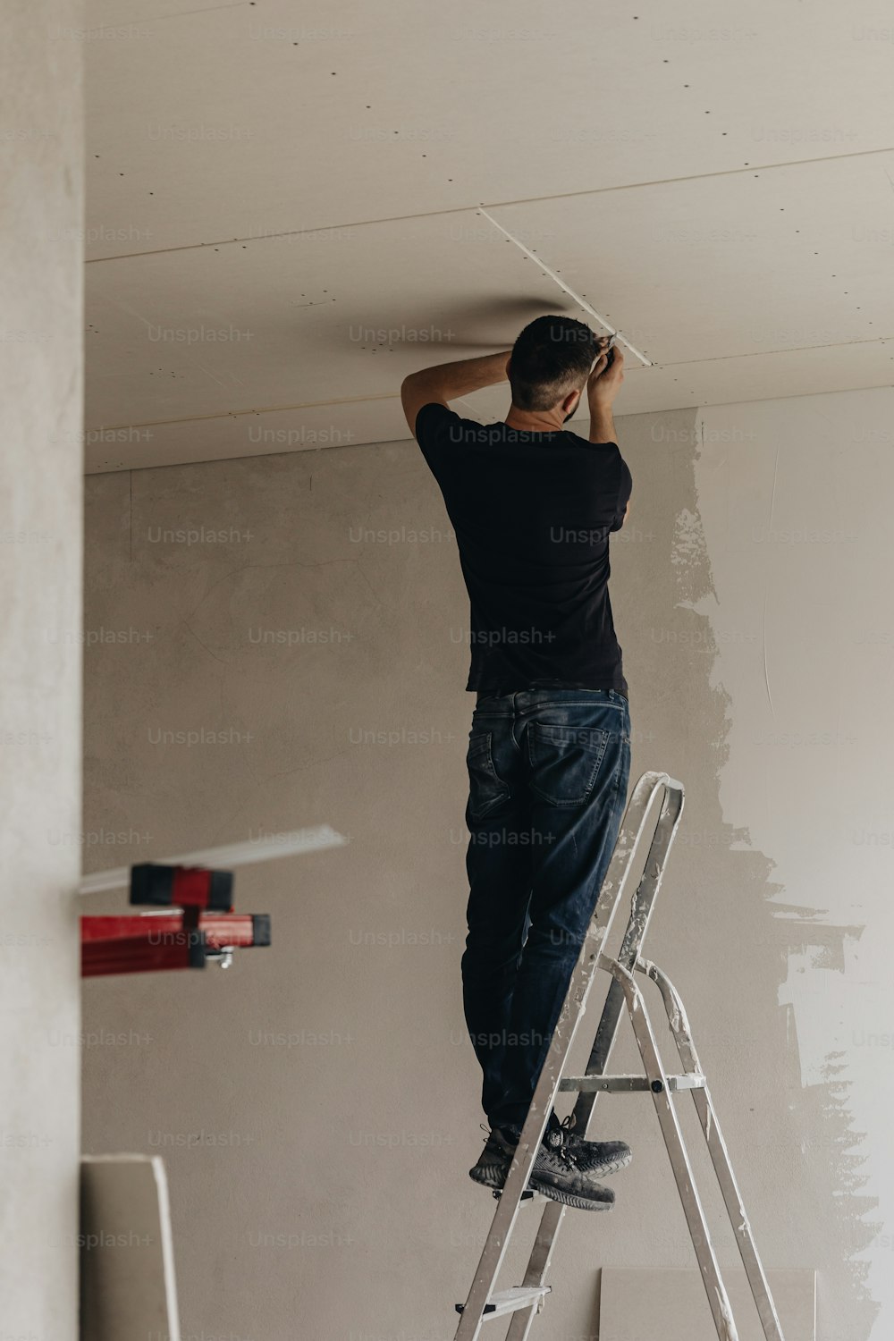 a man standing on a ladder painting a wall