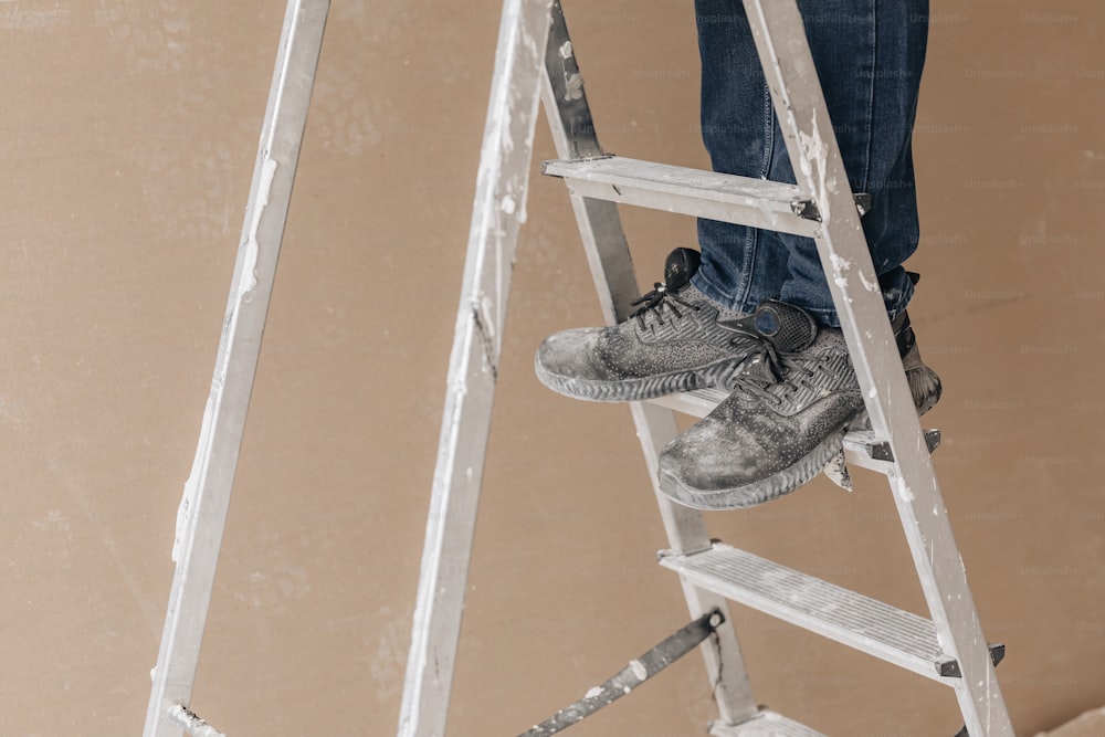 eine Person, die mit einem Paar Schuhe darauf auf einer Leiter steht