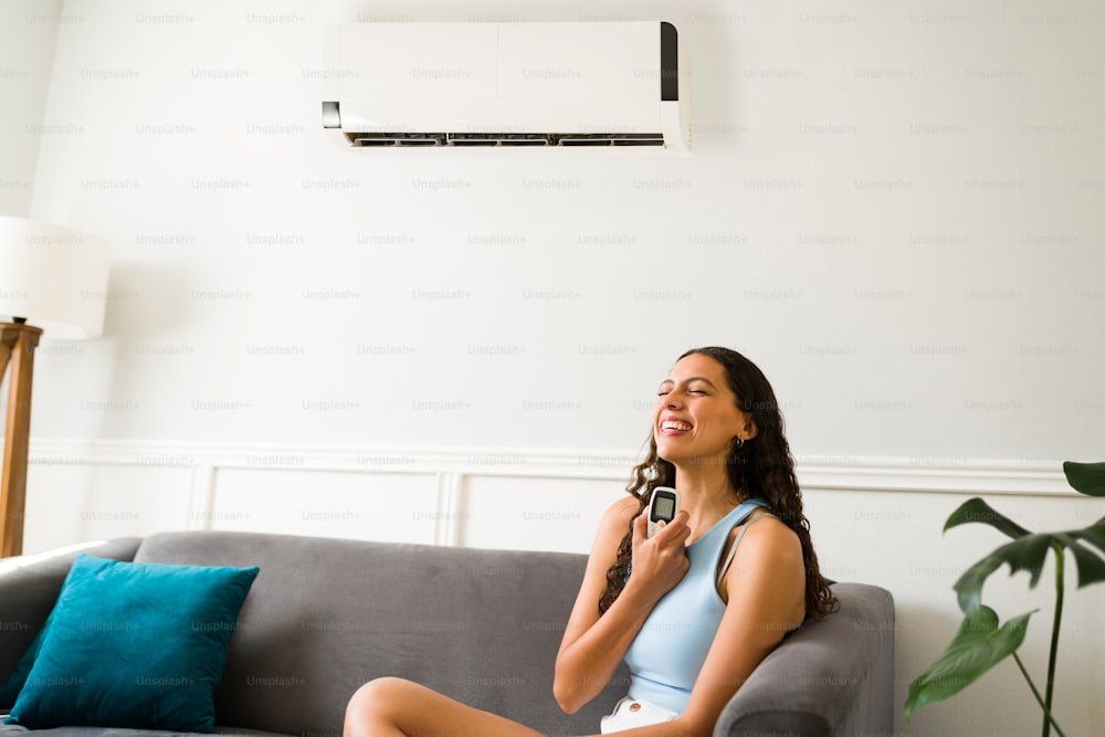 Beautiful woman laughing in the living room while feeling happy for her new air conditioner at home