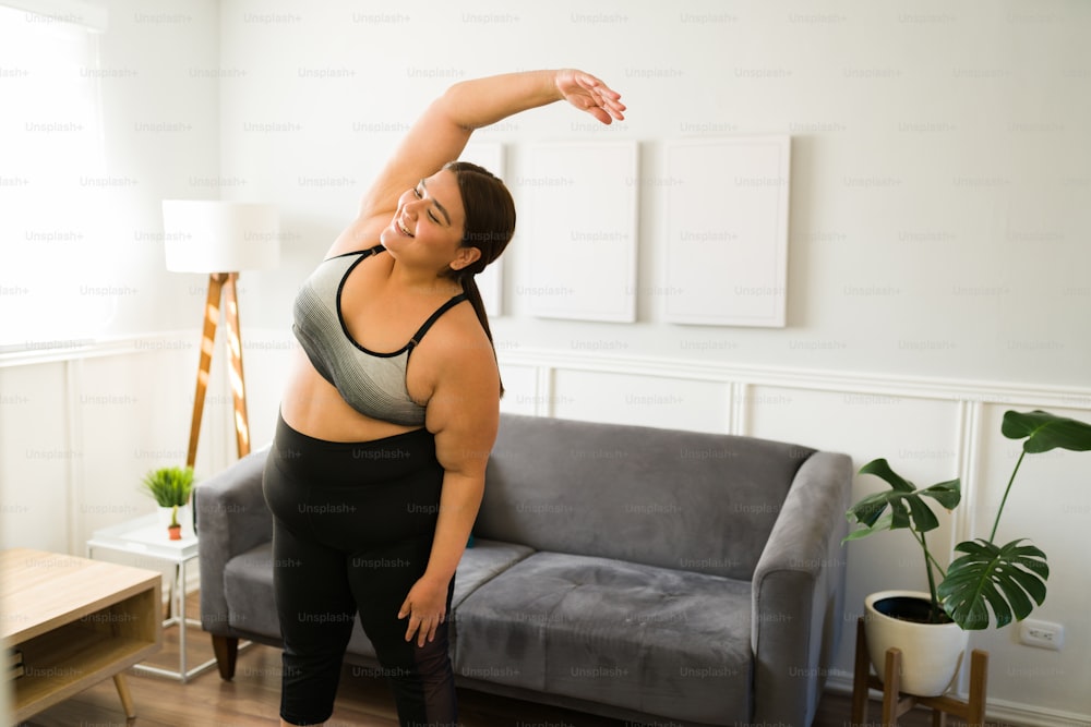 Foto Alegre joven gorda sonriendo mientras disfruta de un entrenamiento en  casa. Mujer obesa haciendo ejercicios cardiovasculares – Yoga Imagen en  Unsplash