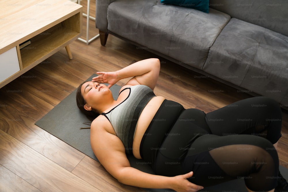Angolo alto di una donna stanca in sovrappeso che si sente esausta dopo un duro allenamento cardio