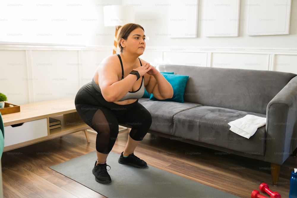 Donna in sovrappeso attiva che prova un nuovo stile di vita sano e si esercita mentre fa squat