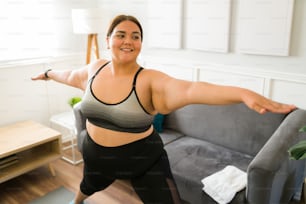 Cheerful fat young woman smiling while enjoying a home workout. Obese woman doing cardio exercises