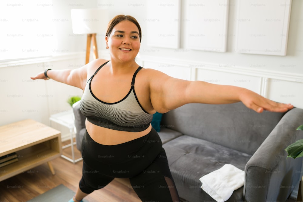 Cheerful fat young woman smiling while enjoying a home workout. Obese woman doing cardio exercises