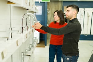 Young husband and caucasian wife trying stainless steel water faucets for their new bathroom