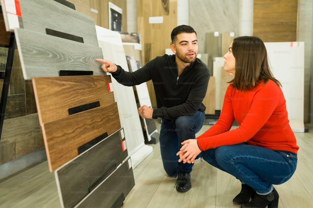 Handsome man speaking with his wife about buying new wooden floors at the store