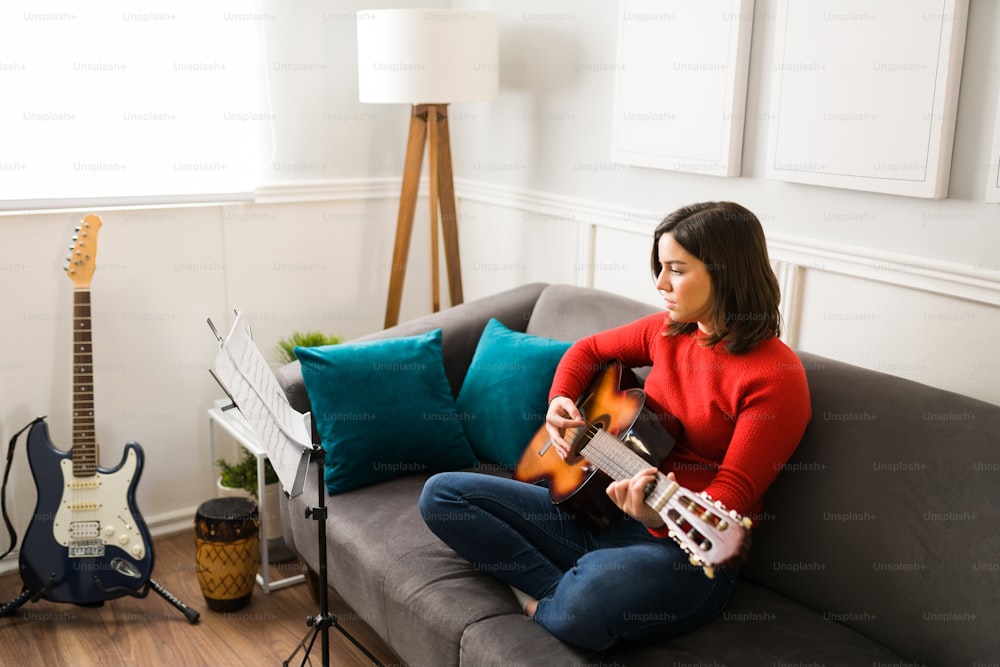 Bella donna che impara e prova una canzone con la chitarra. Musicista femminile che compone nuova musica