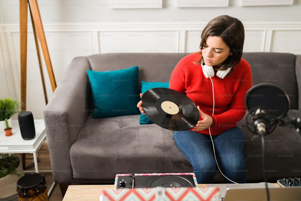 Attractive young woman putting a vinyl record on the turntable to get inspiration to compose new music