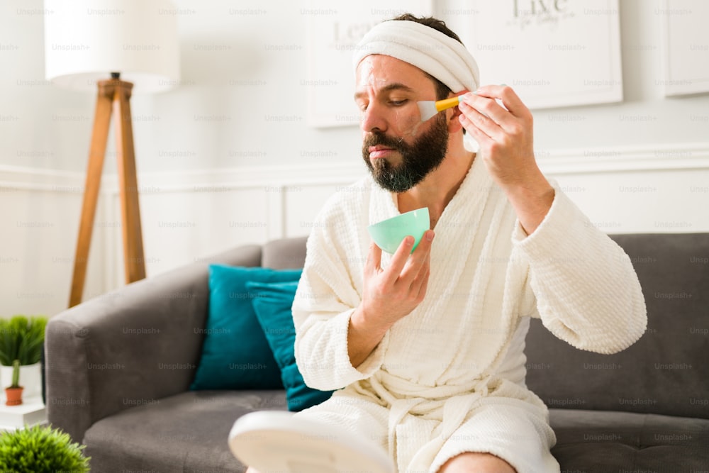 Using a serum. Bearded hispanic man applying moisturizing oil for a healthy skin