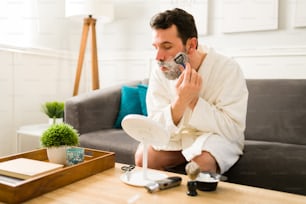 I want a clean face. Young man shaving his beard with a disposable razor before going out