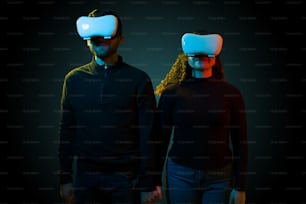 Happy couple holding hands while experiencing the virtual reality metaverse. Beautiful woman and man with a VR headset