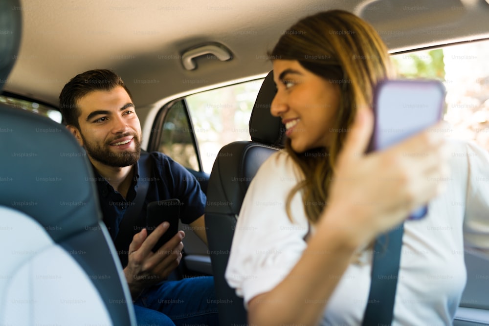 Happy female driver and passenger looking at the GPS on the mobile app on the smartphone while driving to a destination