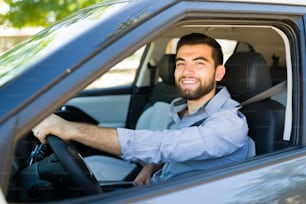 Cheerful young man smiling while going to the office in the morning and driving his car
