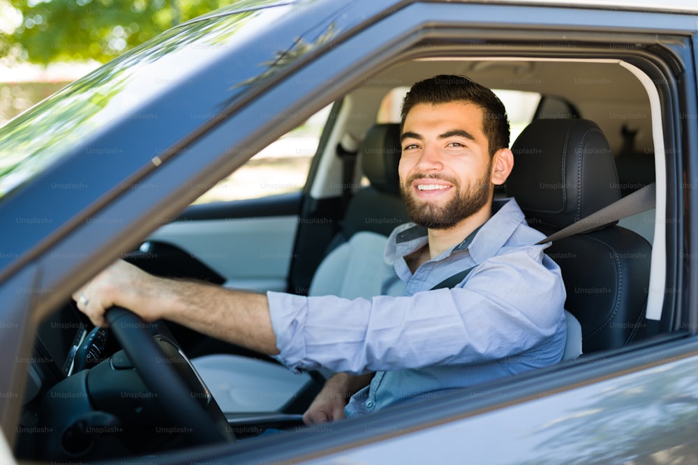 Cheerful young man smiling while going to the office in the morning and driving his car