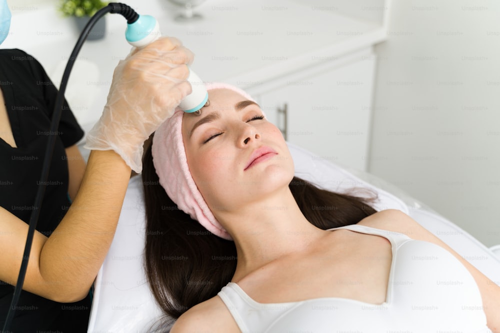 Anti aging treatment. Beautiful young woman relaxing with her eyes closed while getting a beauty RF procedure at the spa