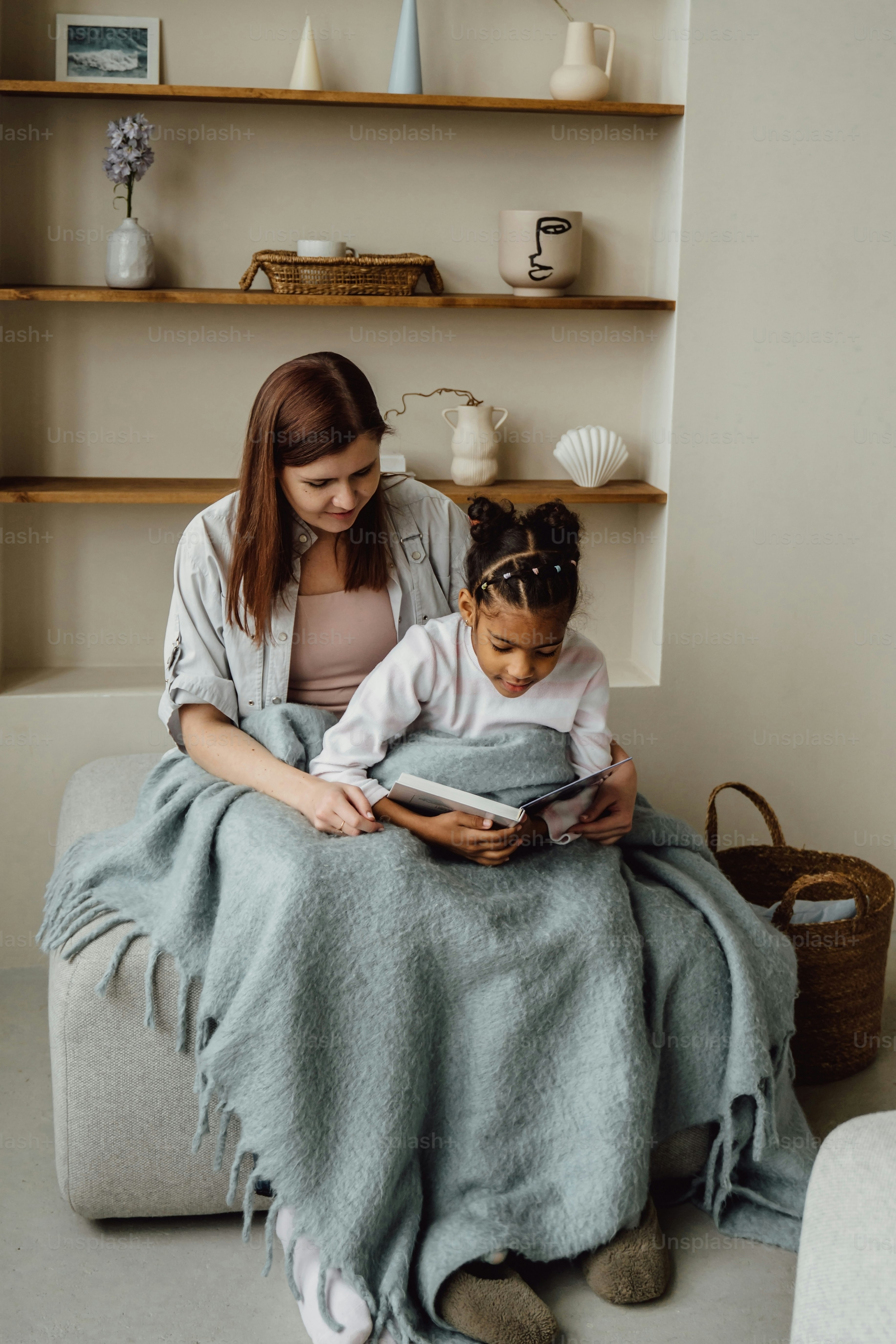 a woman and a child sitting on a couch under a blanket
