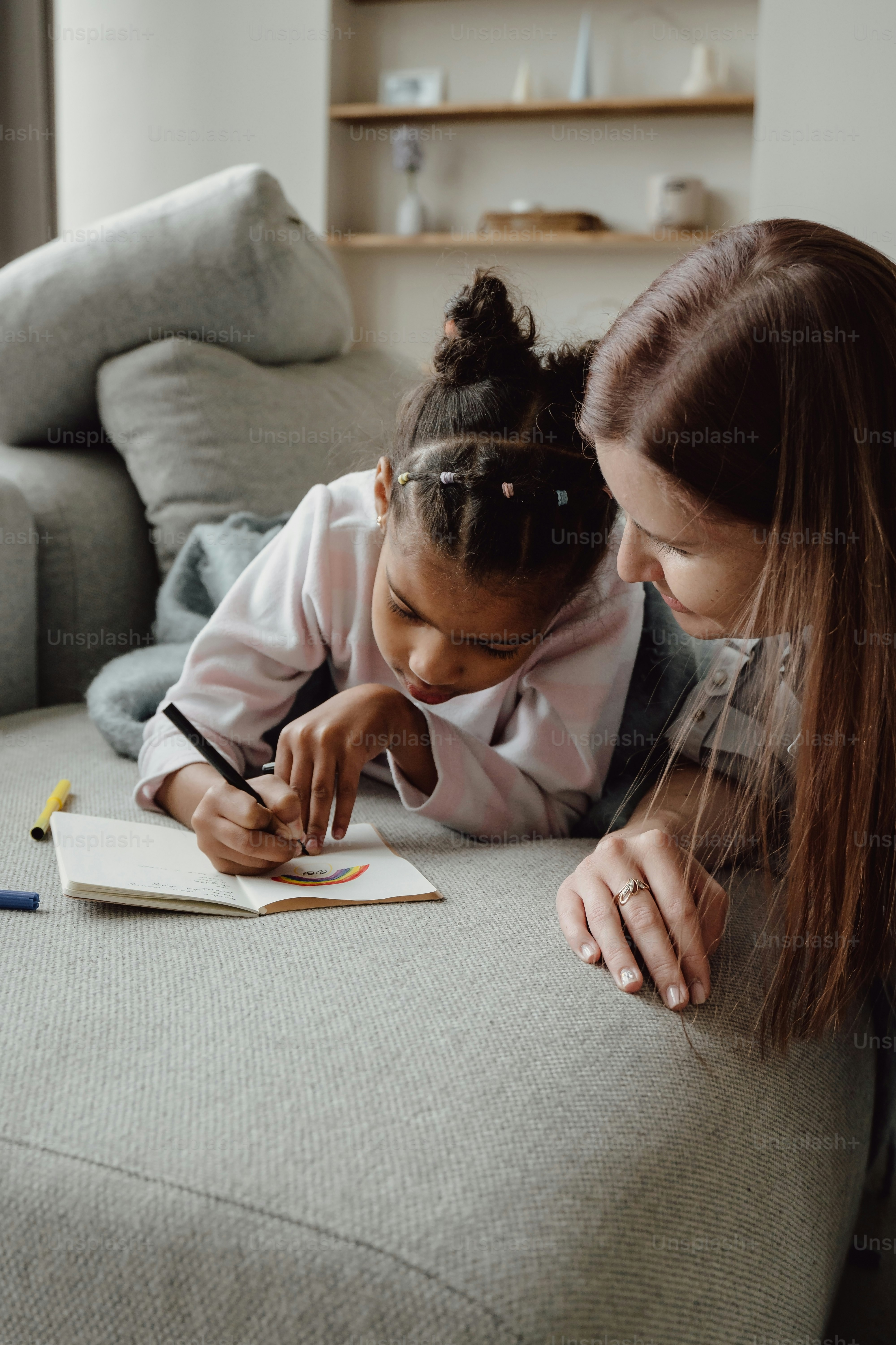 a woman sitting on top of a couch next to a little girl