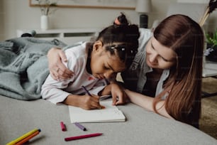 a woman and a young girl writing on a notebook