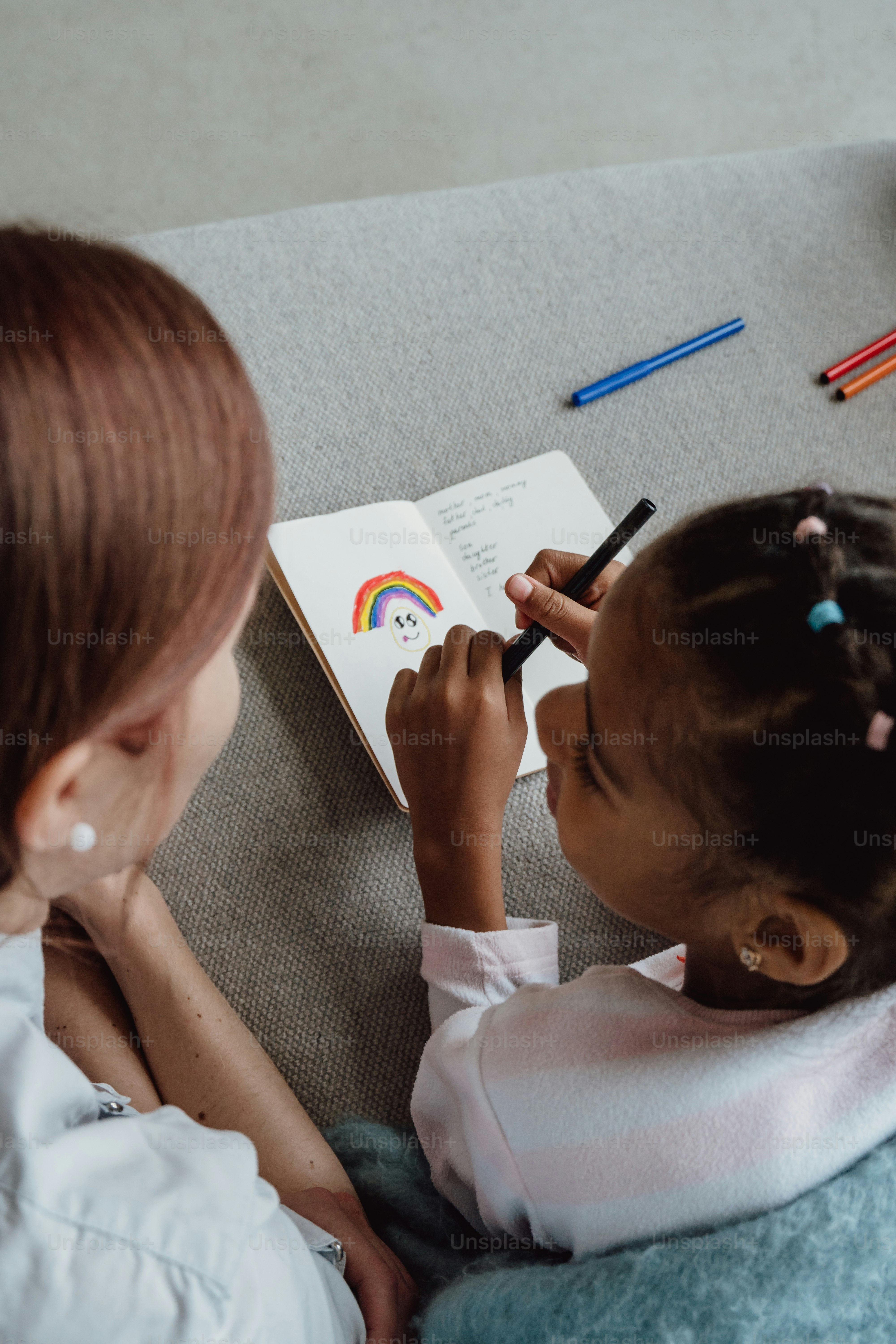 a little girl sitting on a couch writing on a book