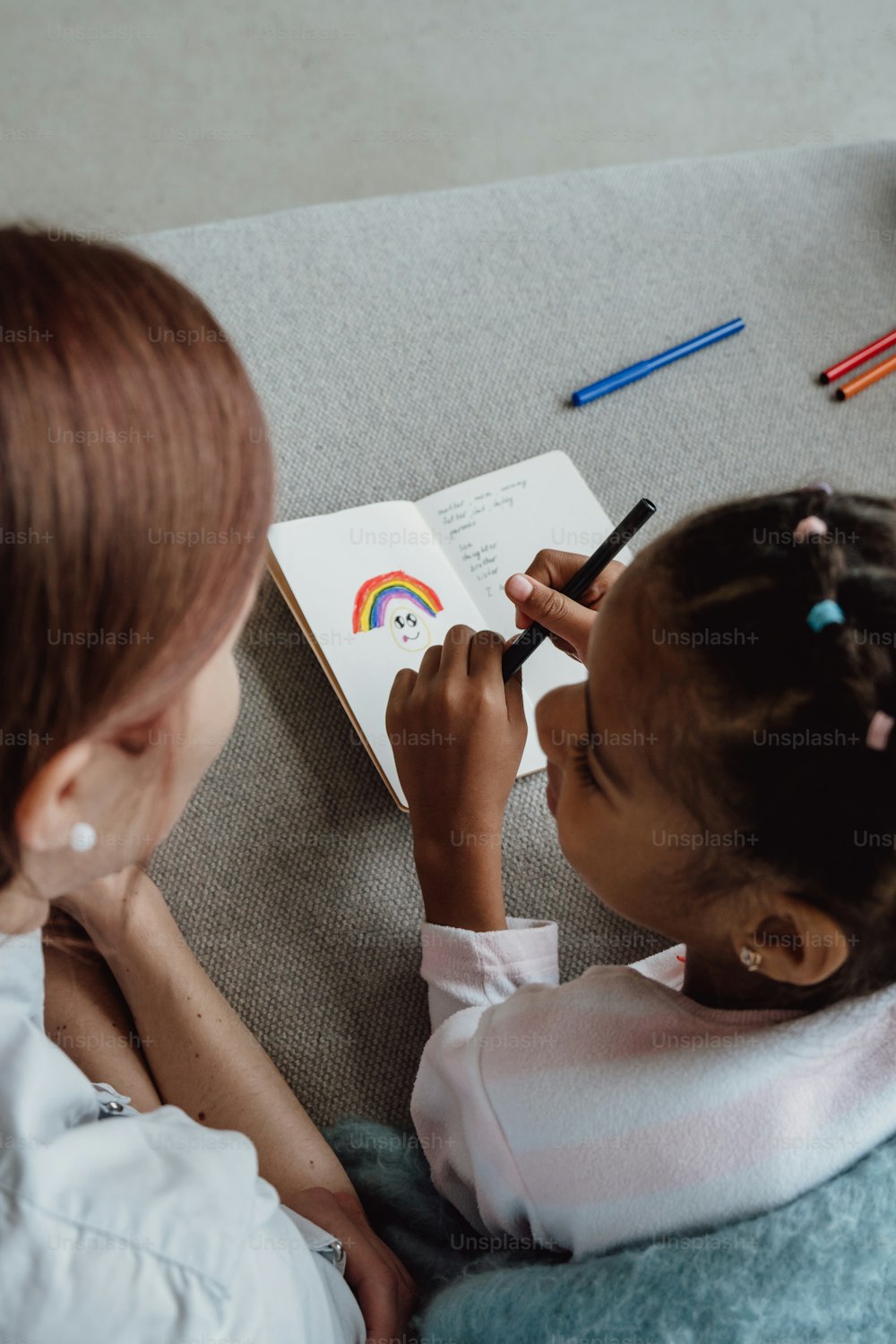 Une petite fille assise sur un canapé écrivant sur un livre