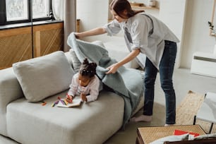 a woman helping a little girl with a book on a couch