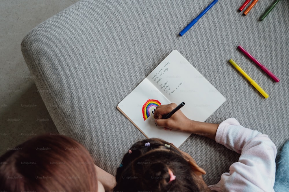 a little girl sitting on a couch writing on a book