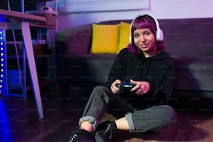 Relaxed beautiful gamer looking at the camera and smiling while playing video games at home