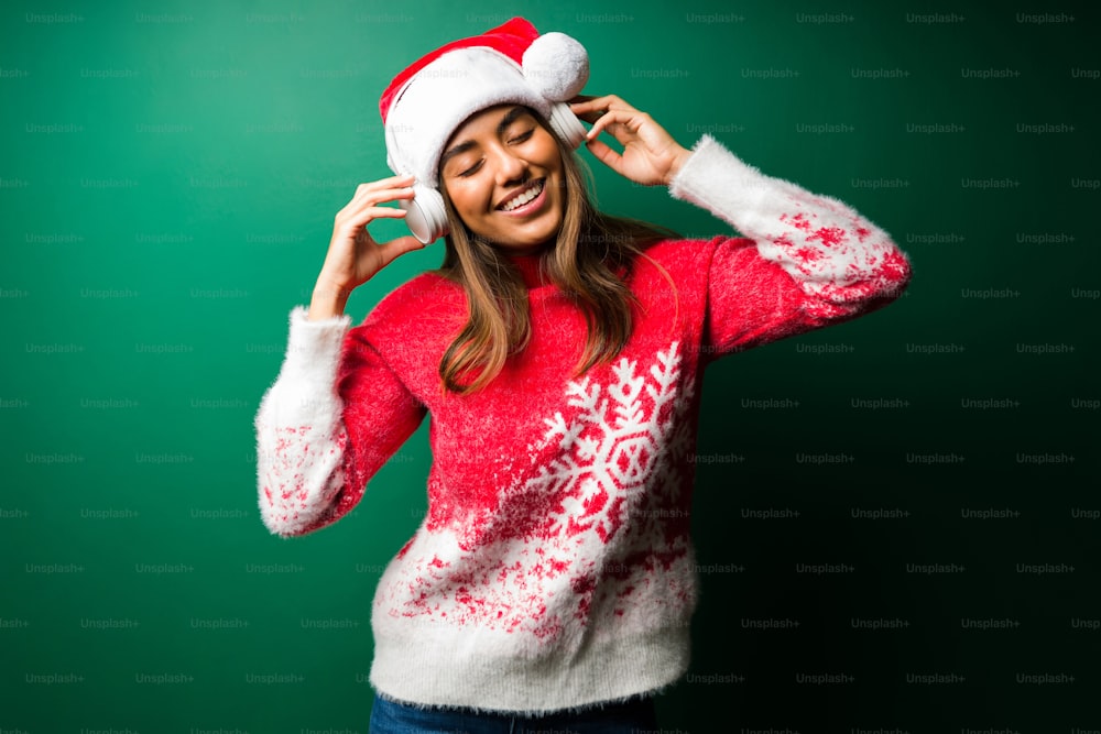 즐거운 시간 보내세요. 크리스마스 모자를 쓴 흥분한 젊은 여자 무선 헤드폰으로 행복한 음악을 듣고 있다