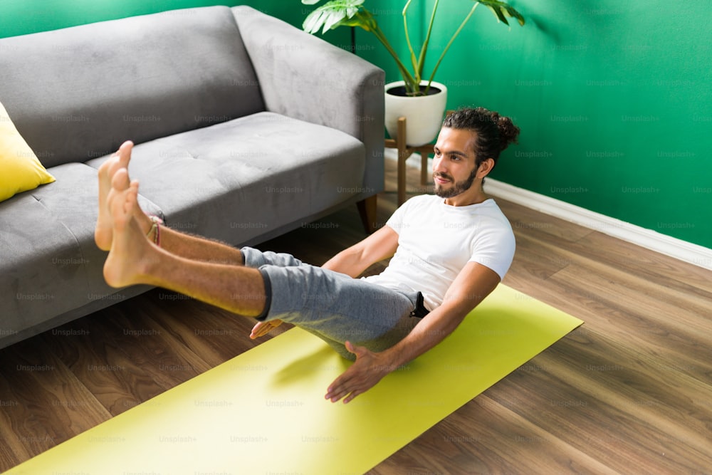 Attractive young man working on his balance and body strength with a boat yoga pose on an exercise mat